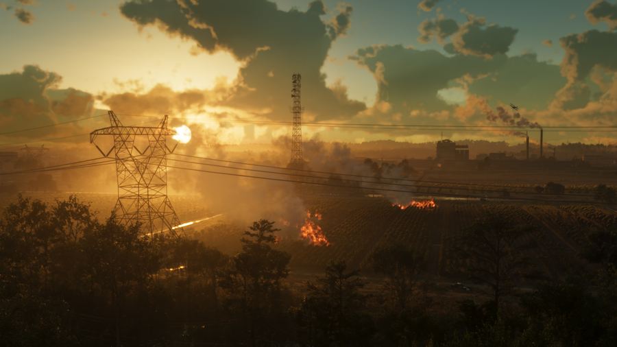 Power lines and an industrial plant silhouetted against a burning orange sunset