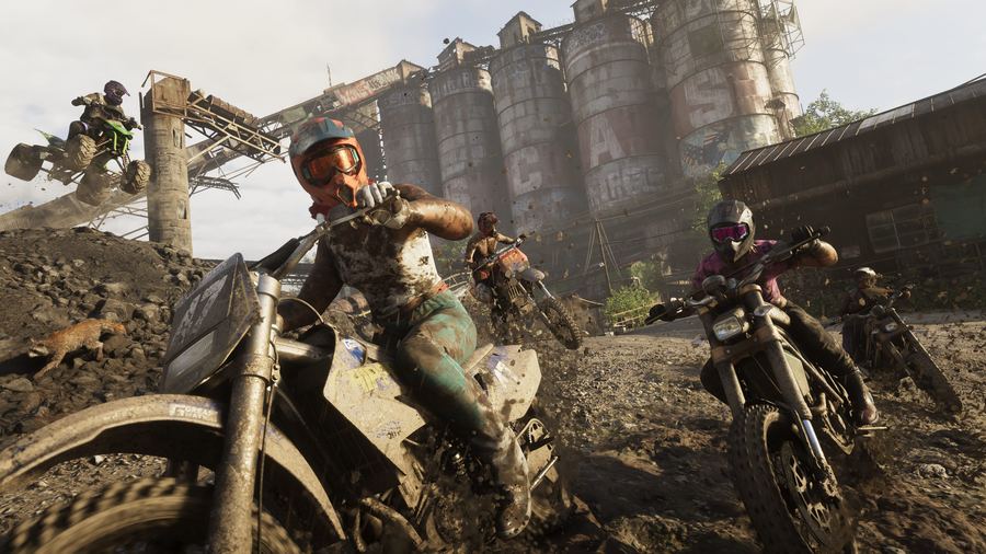 Two riders on dirt bikes at a derelict industrial site