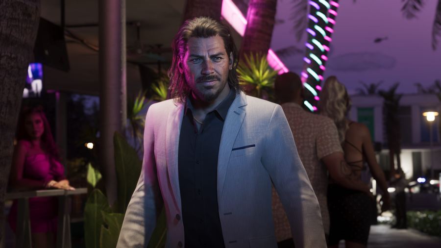 Raul Bautista in a white suit jacket walking through a neon-lit venue